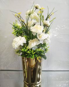 a gold vase filled with white flowers on top of a table