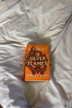 a court of silver flames by sarah i maas on a white bed sheet