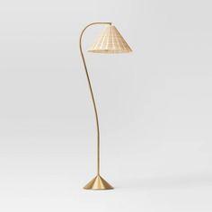 a floor lamp with a white shade on it's side and a gold base