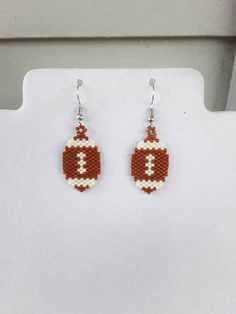 the beaded football earrings are made with red and white beads, which have been stitched together