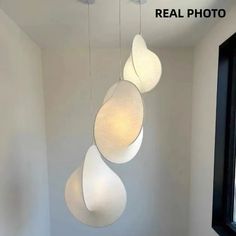 three lights hanging from the ceiling in a room with white walls and flooring, one is