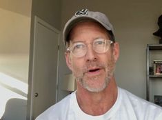 a man wearing glasses and a baseball cap is making a funny face at the camera