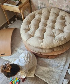 a small child standing next to a chair and ottoman on the floor in a room