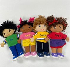 five dolls are lined up in the same row and one is wearing a happy shirt