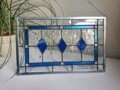 a blue stained glass window sitting on top of a table next to a potted plant