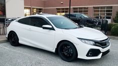 a white honda civic is parked in front of a brick building with black rims