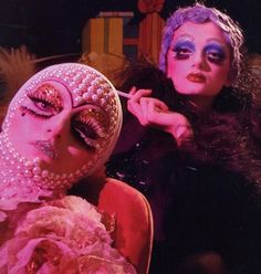 two women dressed in costume and make up posing for the camera with their eyes closed