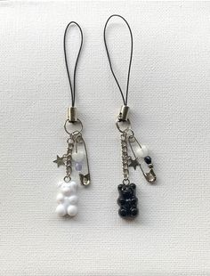 two key chains with charms attached to them on a white surface, one is black and the other is white