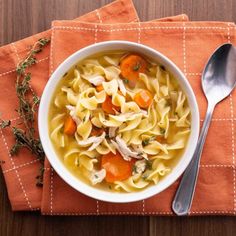 a bowl of chicken noodle soup on an orange napkin