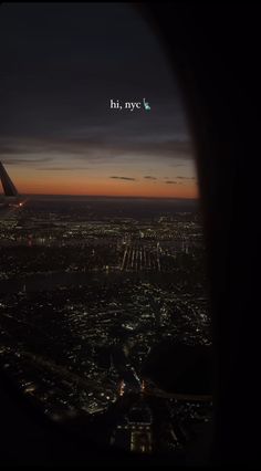 the view from an airplane window at night, looking down on city lights and buildings