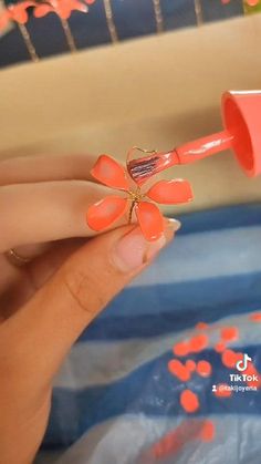 a woman is holding an orange and pink flower shaped toothbrush in her left hand