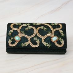 This book bag is a unique and beautiful piece of accessory, made from luxurious green velvet that gives it a rich and soft texture. The turquoise stone inlaid in the center of the bag adds a pop of color and elegance, making it stand out from the rest. The floral pattern embellished with metal threads is intricate and sophisticated, and it has been delicately handcrafted to add a touch of glamour to the bag. The metal threads, shining under the light, bring an extra touch of luxury and add to the overall aesthetic of the bag. The bag is spacious enough to carry all your essentials, such as books, notebooks, and a small laptop. Its generous size makes it ideal for use as a school bag, a work bag, or for traveling. The green velvet and turquoise stone combination makes this book bag not only Elegant Green Embroidered Shoulder Bag, Luxury Handmade Green Shoulder Bag, Luxury Green Handmade Shoulder Bag, Luxury Embroidered Green Bag, Luxury Green Embroidered Bag, Luxury Embroidered Velvet Bag, Luxury Green Rectangular Clutch, Designer Green Rectangular Clutch, Elegant Turquoise Bag For Gift