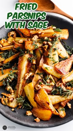 fried parsnips with sage on a black plate next to a wooden spoon