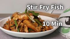 stir fry fish is in a white bowl with chopsticks next to it on a table