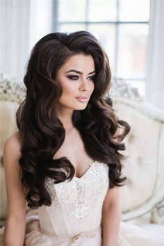 a woman in a wedding dress sitting on a couch with her hair down and wearing a tiara