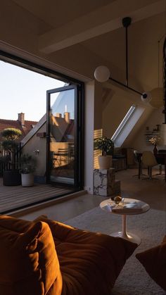 a living room filled with furniture next to an open roof top window overlooking the city