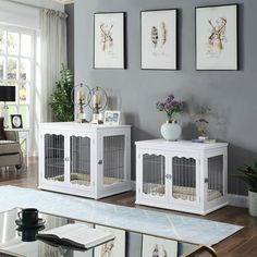 a living room filled with white furniture and pictures on the wall above each pet cage