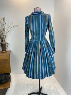 "1960's Blue And Green Stripe Shirt Dress This is such a great shirt dress. The stripes and the careful placement of them make this shirt dress next level attractive. Just check out the pictures and see how the stripes were perfectly utilized to make a regular cut shirt dress into something special. This dress is a button front closure, has her makers tag, which is frayed. Maker is Carol Rodgers Juniors Measurements provided are flat and have been doubled. Bust 34\" Waist 25\" Hips free\" Length Fitted Striped Shirt Dress For Fall, Fitted Striped Shirt Dress With Buttons, Striped Fitted Cotton Shirt Dress, Fitted Striped Cotton Shirt Dress, Vintage Striped Dresses For Work, Vintage Striped Dress For Work, Fitted Striped Long Sleeve Shirt Dress, Fitted Striped Collared Dress, Vintage Striped Workwear Dresses