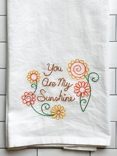 a white towel with embroidered words on it that says you are my sunshine and flowers