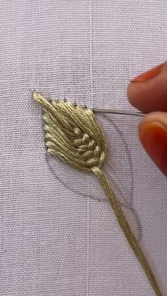 someone is stitching the thread on to a piece of cloth with gold colored thread