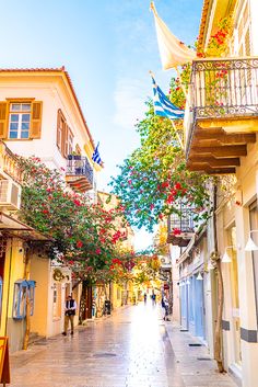 an empty street with people walking down it and flowers on the trees lining the sidewalks