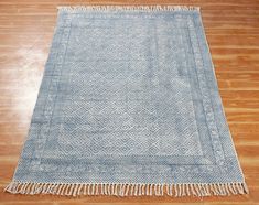 a blue and white rug with tassels on top of wooden floor next to hard wood flooring