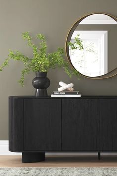 a black sideboard with two vases and a mirror on the wall behind it