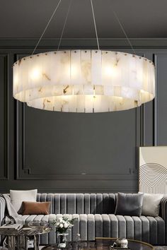 a modern living room with grey walls and white couches, round chandelier over the coffee table