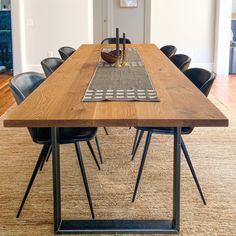 a wooden table with black chairs and a rug on the floor in front of it