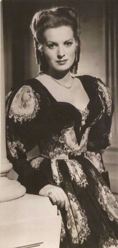 an old black and white photo of a woman wearing a dress with lace on it