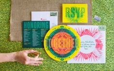 a person holding a yellow frisbee next to some cards and envelopes on a table