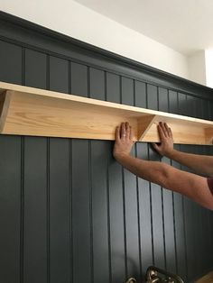 a man is working on a shelf in the kitchen with his hands holding it up