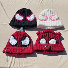 three knitted beanies with eyes and noses on top of a bed sheet in the sun