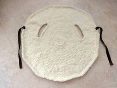 a white round rug with black straps on the floor next to a cat's head