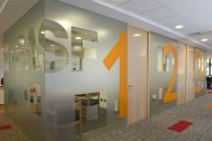 this is an office with glass walls and orange arrows on the wall, along with carpeted flooring