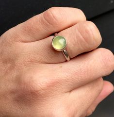 A stunning apple green 8mm prehnite has been set in sterling silver with a handmade ring band from sterling silver half dome wire. This ring is simple and elegant. The prehnite has inner striations that are natural for prehnite and add extra visual interest to a lovely stone. Made to order! Green Sterling Silver Minimalist Ring, Green Minimalist Sterling Silver Ring, Round Green Prehnite Jewelry, Green Prehnite Round Jewelry, Prehnite Gemstone Ring Jewelry, Handmade Green Moonstone Ring In Sterling Silver, Green Moonstone Sterling Silver Ring, Adjustable Green Moonstone Ring In Sterling Silver, Adjustable Green Moonstone Sterling Silver Ring