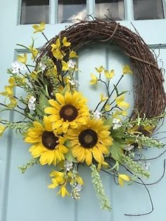 a wreath with sunflowers and greenery is hanging on the front door,