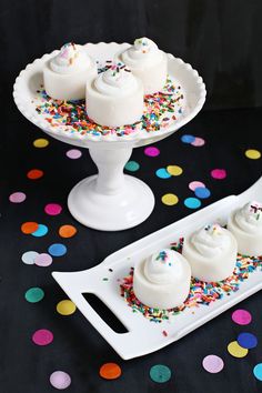 three white desserts with sprinkles on a cake platter and confetti