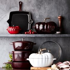 a kitchen shelf filled with dishes and pans on top of each other next to a cutting board