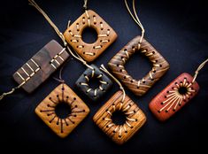 four wooden ornaments hanging from strings on a black surface, one with holes in the middle