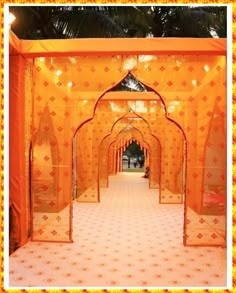 an orange and white wedding setup with draping, flowers and greenery on the floor