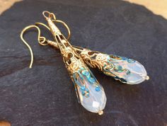 Elegant dangle earrings in gold with an opal (synth) that show beautiful sparks in the sun in light sky blue and sunny gold. The tear drop opals are facetted and remind also of moonstones and of oriental jewelry, of Art Deco, Art Nouveau and of paintings, where mysterious sorceresses prepare magic potions, illuminated by the fire. So this is a perfect gift for a fairy elf white-witchy woman who will certainly see this jewelry looks like a magic wand... I added verdigris patina to the tips and ma Nickel-free Gold Art Nouveau Jewelry, Gold Nickel-free Art Nouveau Jewelry, Art Nouveau Dangle Earrings For Gifts, Art Nouveau Dangle Earrings Gift, Gold Fantasy Handmade Earrings, Gold Handmade Fantasy Earrings, Handmade Gold Fantasy Earrings, Fantasy Style Drop Earrings Jewelry Gift, Fantasy Style Drop Earrings For Gift