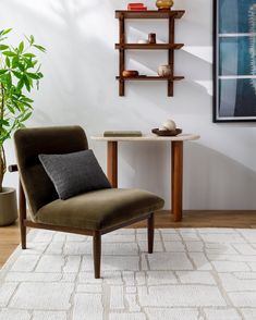 a chair sitting in front of a table on top of a white rug next to a potted plant