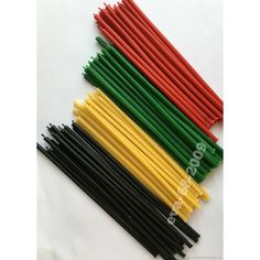 several different colored straws are lined up on a white surface with black, yellow, and green stems