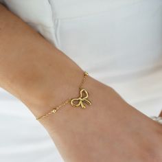 a woman wearing a gold bracelet with a bow on it