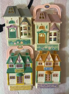 three small toy houses sitting next to each other on a white carpeted floor,