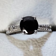 a black diamond ring sitting on top of a white furnishe covered surface,