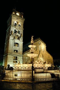 a large building with a fountain in front of it and a clock tower at night