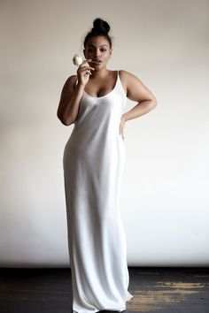 a woman in a long white dress posing for the camera with her hands on her hips