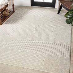 a white rug in the corner of a room with a bench and potted plant